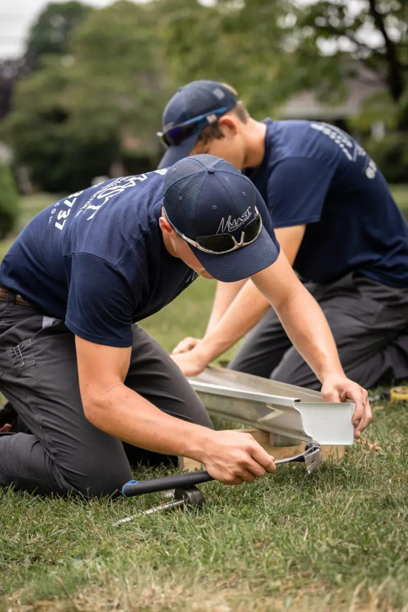 Roofer working on gutter components on the ground.